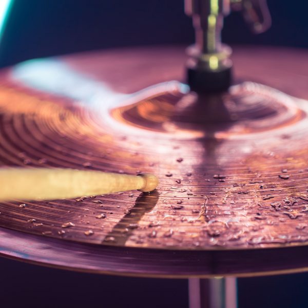 Hi-hat close-up of plates with drumsticks on a background of colored lanterns. Water drops on plates. Musical concept with a working drum.